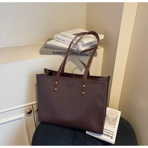 Macro detail of dark brown leather tote bag with metallic rivet accents on blue striped stool