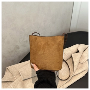 Close-up of minimalist brown suede bucket bag with fine stitching and leather shoulder strap