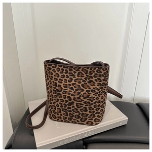 Detail of leopard print bucket bag with brown leather strap on a decorative book