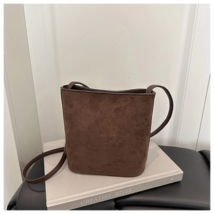 Detail of dark brown suede bucket bag texture with slim leather shoulder strap