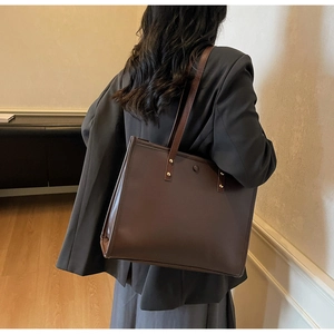Detailed side view of a large vintage brown leather tote bag worn by a model