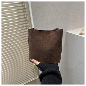 Detail of a dark brown suede bucket bag featuring minimalist texture and sleek design