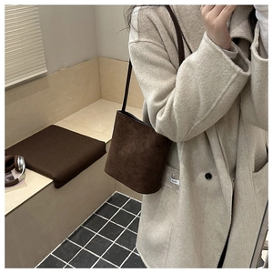 Dark brown suede bucket bag worn by model in a minimalist lifestyle setting