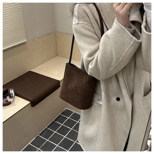 Detail view of dark brown frosted suede bucket bag featuring minimalist retro design
