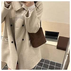 Mirror selfie showing a brown suede bucket bag styled with a beige wool coat