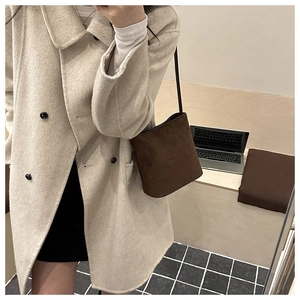 Brown suede shoulder bucket bag shown in a stylish urban lifestyle setting with laptop