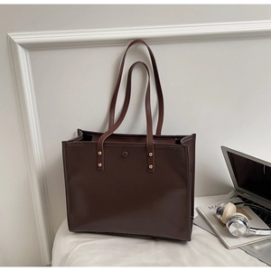 Detail view of large brown vintage tote bag with gold rivets and secure magnetic buckle