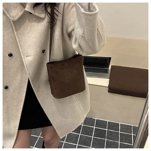 Brown suede bucket bag styled with a beige coat and black skirt for a chic look