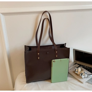 Detailed view of dark brown tote bag interior capacity with a tablet and gold hardware