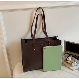 Macro view of a large vintage brown leather tote bag showing rivets and spacious interior