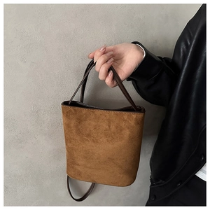 Detail of caramel suede bucket bag showing soft texture and premium leather straps