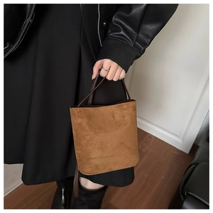 Detail shot of vintage brown faux suede bucket bag with a slim handle in a cozy home setting