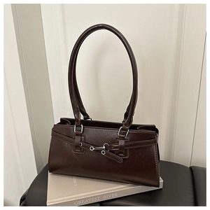 Détail d'un sac à bandoulière rectangulaire marron café avec boucle argentée sur livre