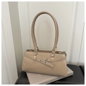 Détail du sac baguette beige avec boucle mors argentée sur un tapis en cuir