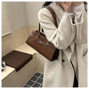 Detail of dark brown vintage leather shoulder bag with silver buckle on beige coat