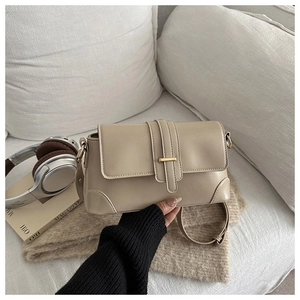 Detail of beige faux leather shoulder bag with gold metal buckle and adjustable strap
