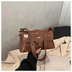 Detail of dark brown vintage handbag with white contrast stitching and gold buckle