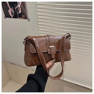 Detail of vintage brown shoulder bag with white contrast stitching and gold buckle