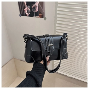 Detail of black faux leather shoulder bag with white contrast stitching and gold buckle