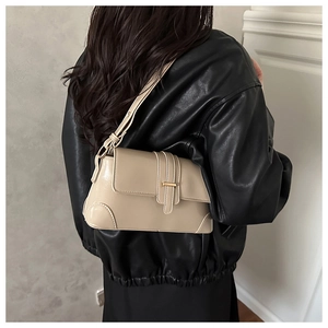 Detail of a beige leather shoulder bag showing the gold buckle and reinforced corners