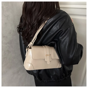 Close-up of beige baguette bag with gold metal buckle on a shoulder strap