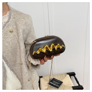 Detail einer dunkelbraunen Ledertasche mit goldener Metallverzierung und feiner Kette