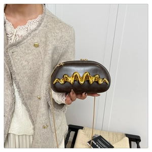 Detail einer braunen Vintage-Clutch mit goldener Wellenprägung und feiner Kette