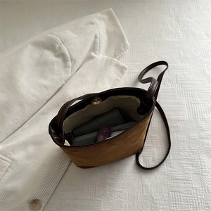 Brown suede bucket bag with magnetic closure showing interior storage and long strap