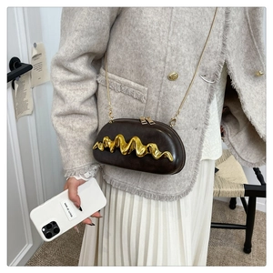 Dettaglio della mini borsa in pelle testa di moro con barra metallica dorata su giacca tweed
