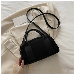 Dettaglio ravvicinato della borsa Boston in camoscio nero su un blazer beige elegante