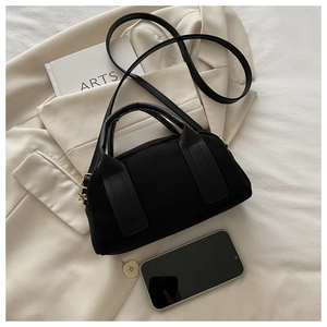 Dettaglio della borsa Boston nera minimalista su un blazer beige per un look di tendenza