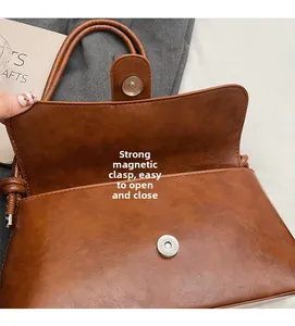 Detail of vintage brown leather bag showing the silver magnetic buckle closure