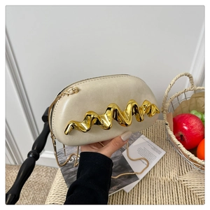 Detail der beige Abendtasche mit goldener Wellenverzierung und eleganter Kette