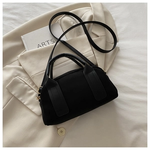 Vista dettagliata di una borsa Boston nera minimalista su un blazer beige elegante