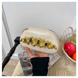 Detail der beigen ovalen Clutch mit goldener Wellenverzierung und Kettenriemen