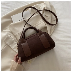 Dettaglio ravvicinato della borsa Boston in pelle scamosciata marrone su blazer