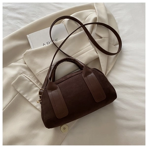 Dettaglio della borsa Boston in camoscio con manici in pelle su un blazer beige