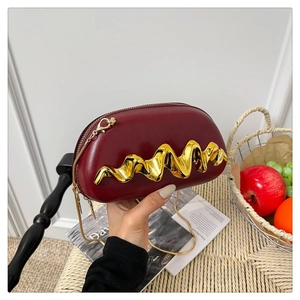 Nahaufnahme der weinroten Muscheltasche mit goldener Wellenmetall-Verzierung