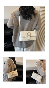 Detail view of cream leather baguette bag with silver buckle and adjustable shoulder strap