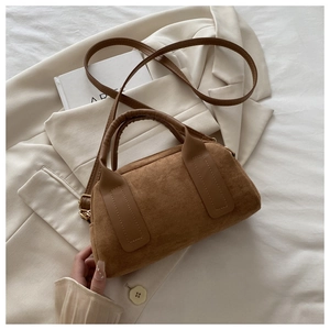 Vista dall'alto borsa Boston in camoscio marrone su blazer beige e libro con cinghie