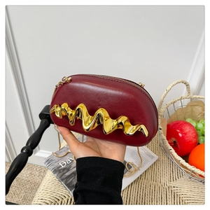 Detail einer burgunderroten Ledertasche mit goldener Wellenverzierung und Metallkette