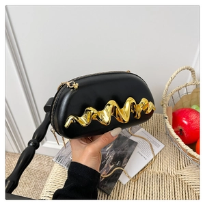 Detail einer schwarzen Ledertasche mit goldenem Wellen-Ornament und feiner Gliederkette