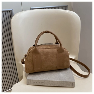 Dettaglio della borsa Boston in camoscio marrone con cinturini in pelle su sedia bianca