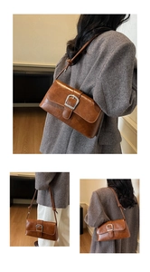 Detail of vintage brown shoulder bag featuring glossy texture and large silver buckle