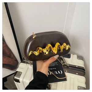 Detail der dunkelbraunen Box-Tasche mit goldener Wellenverzierung und feiner Kette