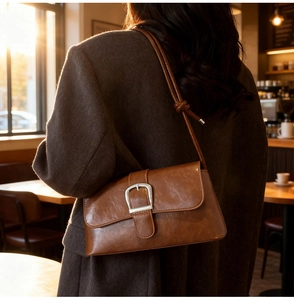 Close-up of a brown leather baguette bag featuring a silver buckle and knotted strap detail