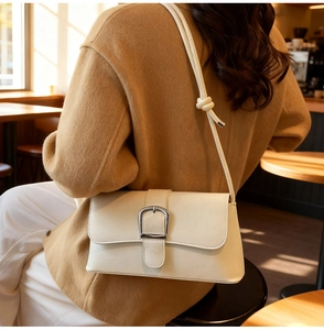 Chic cream leather baguette bag with silver horseshoe buckle shown on a model's shoulder