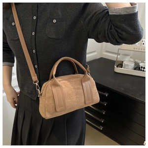 Dettaglio di una borsa Boston in camoscio marrone con fibbie dorate e tracolla lunga