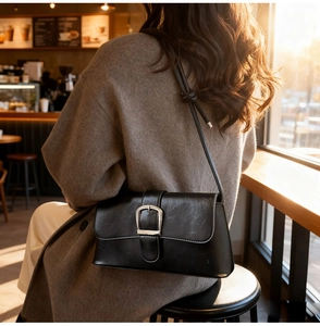 Close-up of black retro patent leather bag with silver buckle and knotted strap details