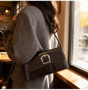 Detailed view of the dark glossy leather bag featuring a large silver horseshoe buckle